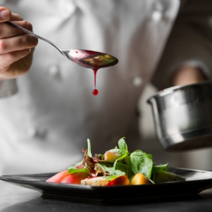 a salad preparation with chef in background representing end user
